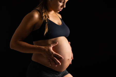 Close-up of beautiful pregnant woman with her hands on her bare bellyの写真素材
