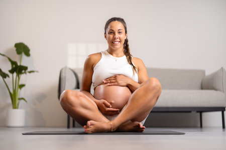 Smiling Pregnant Woman Sitting at Home, Doing Pilates and Yoga Workoutの写真素材