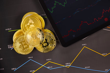 Crypto coins near digital tablet on graphの写真素材