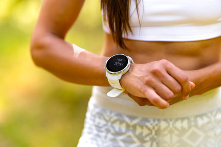 Close-up of woman using fitness smart watch device under workoutの写真素材