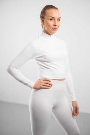 Smiling sporty woman standing with hand on hip