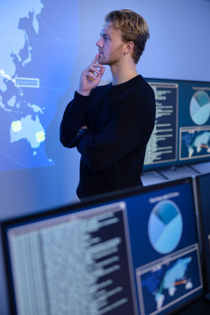 Thoughtful Cyber Security Control Center Operator Working. Multiple Screens Showing Technical Data...