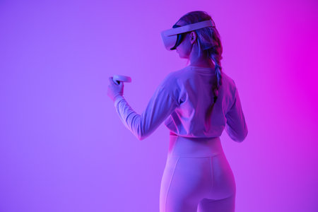 Woman experiencing virtual reality in vibrant neon purple lightingの写真素材