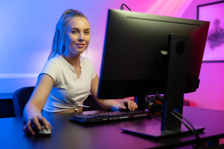 Happy and tired Beautiful Blonde Gamer Girl Playing Online Video Game on Her Personal Computer.の写真素材