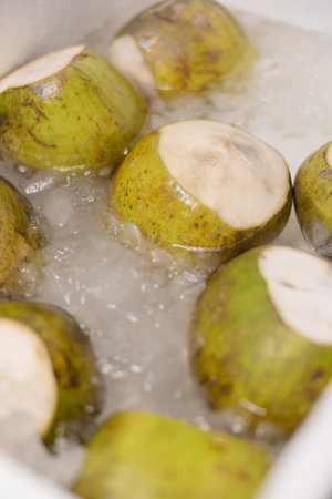Fresh green coconuts chilled in ice, highlighting tropical street food cultureの写真素材