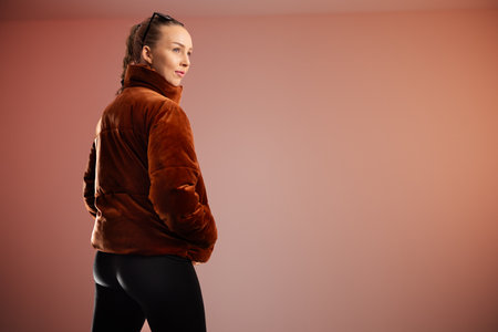 Young woman wearing brown coat posing in modern and clean studio settingの写真素材