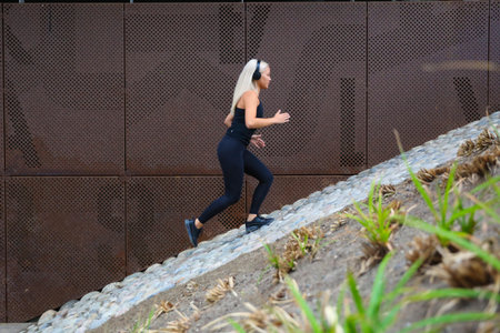 Young woman running uphill in urban area for fitness and exercise
