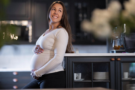 Pregnant woman leaning on kitchen counter in a serene and joyful moment