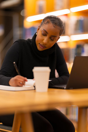Focused student writing in libraryの写真素材