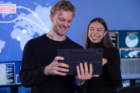 Team collaboration analyzing data on a tablet in a high-tech SOC environmentの写真素材