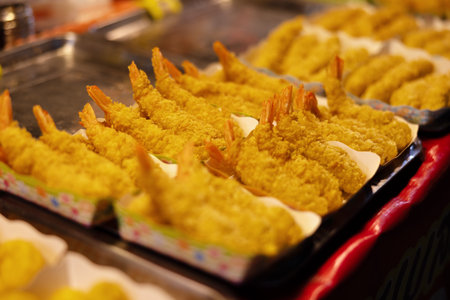 Golden fried shrimps arranged for display in a vibrant street food marketの写真素材