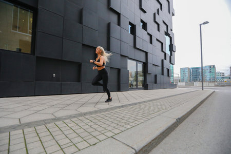 Young woman running near a modern urban building in sportswearの写真素材
