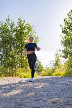 Young woman running outdoors on a scenic trail in activewear gearの写真素材