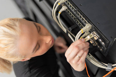 Female IT technician in her 20s working on network equipment in a data center