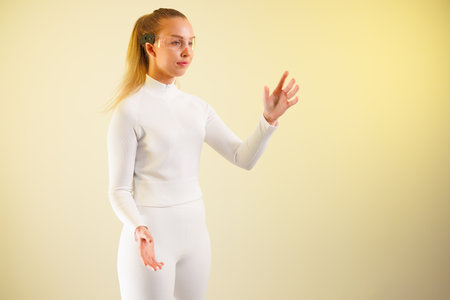 Woman in smartglasses gesturing against yellow backgroundの写真素材