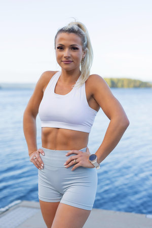 Fit woman outdoors by the water wearing activewear and monitoring fitness progressの写真素材