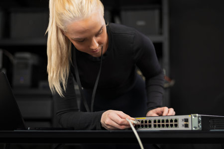 Professional female IT technician configuring a network switch in a modern office setting