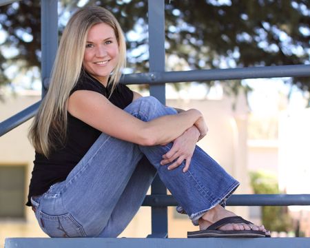 Blond woman sitting in bleachers at a parkの写真素材
