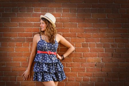 A cute girl standing against a brick wall.の写真素材