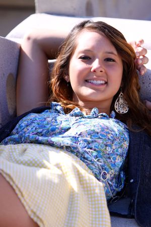 A pretty young girl, reclining on a bench at a park in the sun.の写真素材