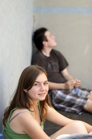 Two kids sitting in the shade in a raquetball court, cooling off on a hot summer day.の写真素材