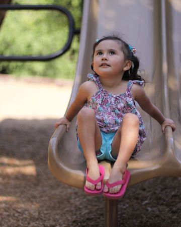 Little girl on a slide looking up at the skyの写真素材