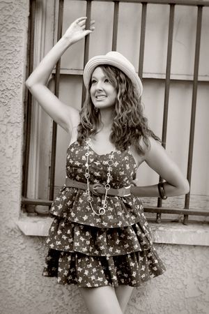 A pretty girl, standing near a window with bars on it, holding onto one of the bars, looking up, happy.の写真素材