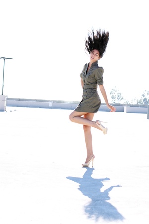 A tall girl in a short dress and high heels with her hair flying up in the air.の写真素材