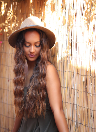 Pretty girl with long hair against a bamboo fenceの写真素材