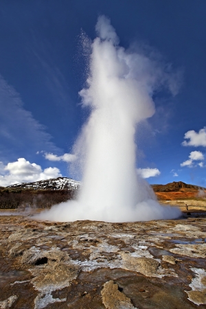 Icelandic Geyser erupts, with blue sky in the backgroundの写真素材