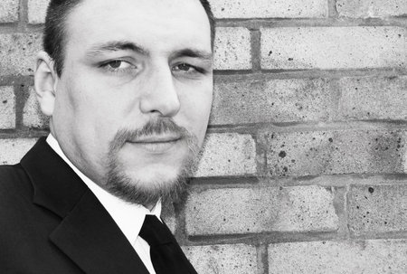 Business man smiling against brick wall