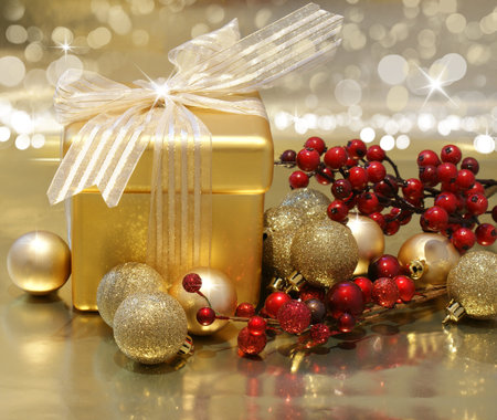 Christmas background with gift box, berries and baubles on gold background