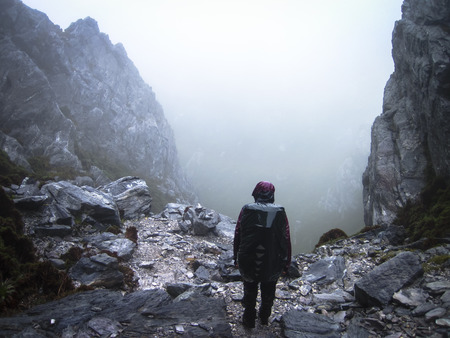 A hiker peers down a steep rocky gully in the Western Arthurs, Tasmania.の写真素材