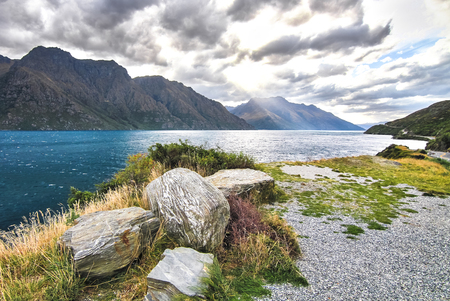 Dramatic lighting and tall mountains at Lake Wakatipu on New Zealand's south island.の写真素材