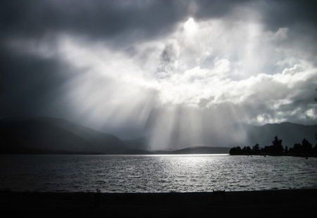 Beams of sunlight pour through the clouds over Lake Te Anau in Fiordland, New Zealand.の写真素材