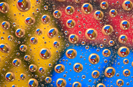 A cube puzzle is reflected in water droplets, giving the appearance that they are floating in space.の写真素材