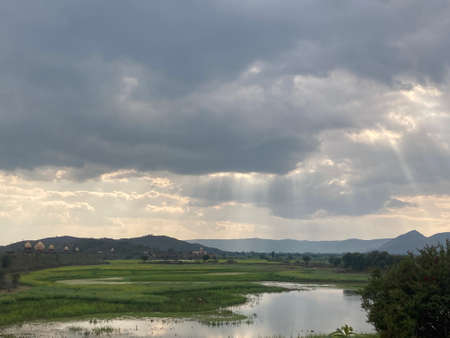 Rural landscape with lake and mountains under cloudy sky. Nature background.の写真素材