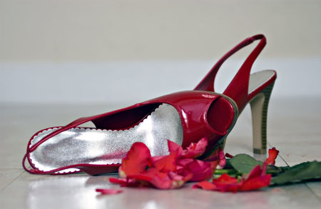 Red high-healed shoes left on the floor next to a crushed rose implying an evening that ended in disappointmentの写真素材