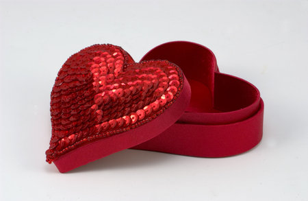 Red sequined heart shaped box with the lid positioned slightly off to the side. 