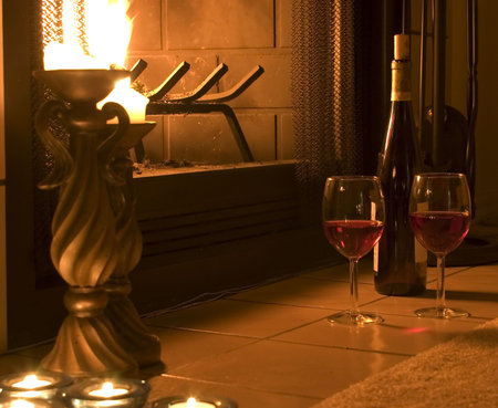 Two wine glasses left in front of a glowing firplaceの写真素材