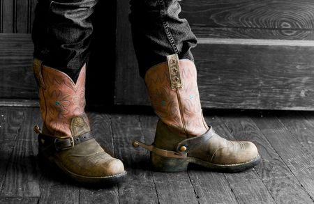 A person standing in fron of an open door, wearing a decorative pair of boots with spurs.の写真素材