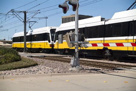 A light rail or cable cars speeding past an activated crossing guardrail. 