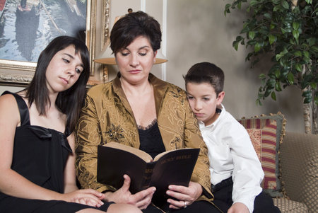 A woman teaches her two children by reading to them from the Bible. 