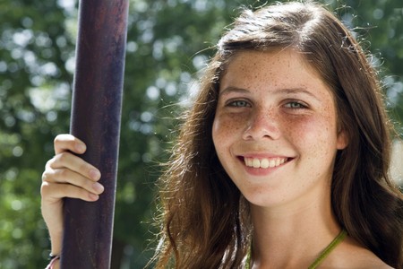 A pretty green eyed, freckled faced teenaged girl smiles a lovely smile for the camera. の写真素材