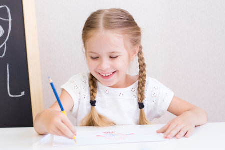 girl is sitting at the table in class writing drawingの写真素材