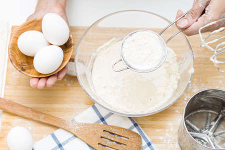 young woman making dough. on the table: flour, eggs, saltの写真素材