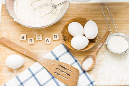 on the table are eggs, salt, flour, and dough. The word bread is laid out. Preparation of the bread
