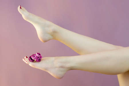 A woman sitting on a couch with her legs gracefully raised - the concept of beauty and skin care. Sugaring, depilation. The health of the feet. Slim, smooth legsの写真素材