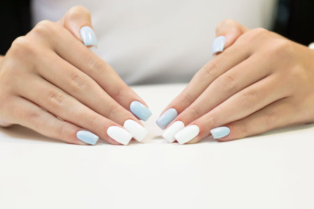 two-tone manicure with blue and white nail Polish on a white backgroundの写真素材