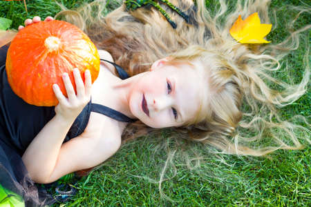 the little girl is dressed in a witch costume, black lipstick. Pumpkin. Halloween. Autumn. Octoberの写真素材